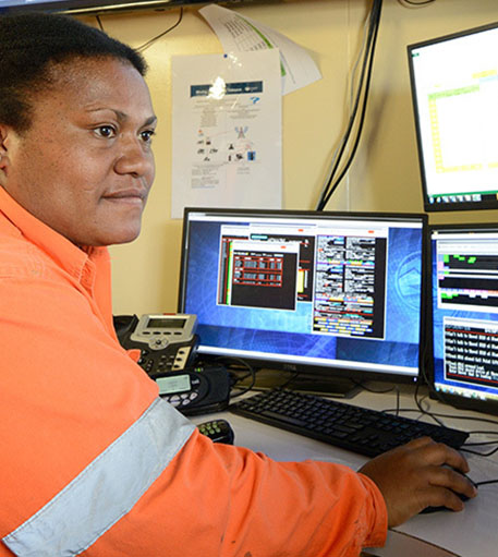 An operator at a computer workstation in a plant control room