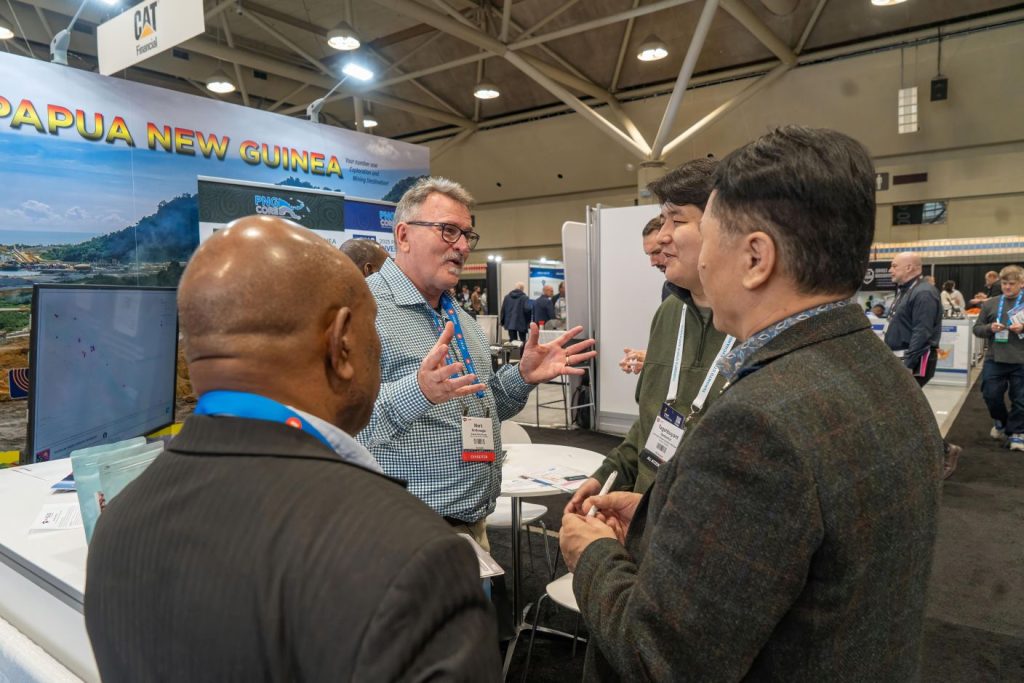 PNGCORE Councillor and Events Committee Chair Mr. Mark McMonagle and MRA officer Sonick Taguse engaging with visitors to the MRA and PNGCORE booth during PDAC.